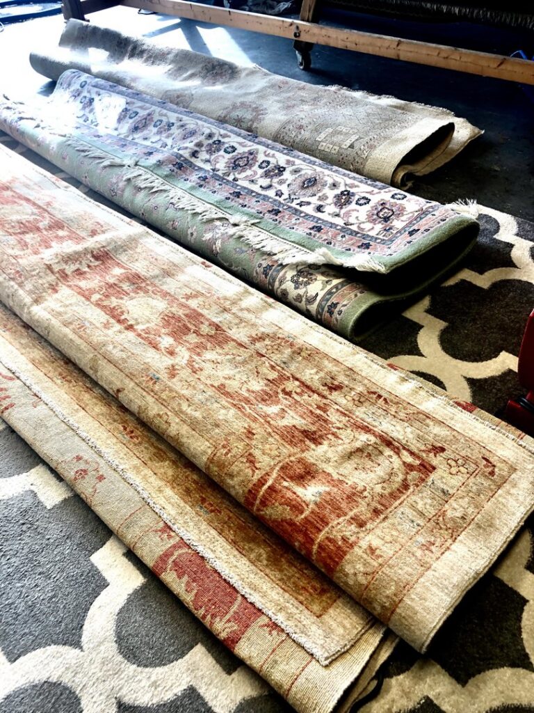 Several rolled-up area rugs, likely awaiting or after cleaning, handled by Celtic Carpet Cleaner in Fort Lauderdale, FL.
