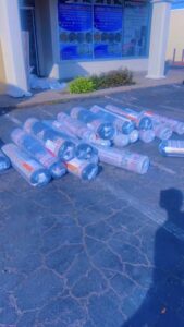 Several rolled carpets wrapped in plastic lying on the asphalt outside Afghan turk carpet online in Sacramento, CA, ready for delivery.