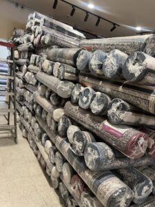 A large stack of rolled carpets wrapped in plastic, ready for sale or installation at Afghan turk carpet online in Sacramento, CA.