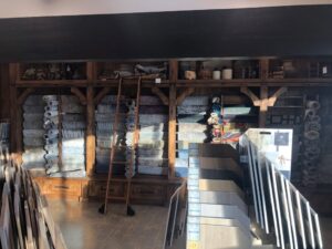 Rolled rugs on shelves and flooring samples displayed in the showroom of Artifacts Fine Rugs and Flooring in South Salt Lake, UT.