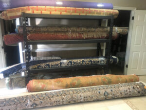 Various rolled rugs neatly stored on shelves, ready for service or delivery by Rug Renew in Spring Valley, CA.