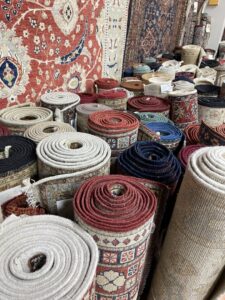 Numerous rolled and stacked oriental rugs ready for selection at Khazai Rugs in Lexington, KY