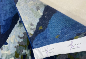 A rolled-up blue abstract rug with a Legacy Looms label, showcasing quality craftsmanship in Minneapolis, MN.