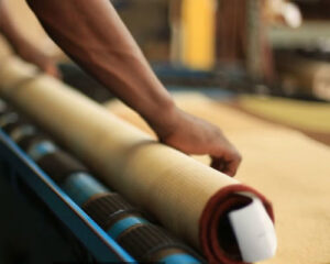 A worker carefully rolling a rug onto a cleaning or drying machine at George Bell Rug Cleaning & Restoration in Jackson, MS.