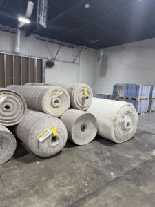 Large rolls of carpet material stored in a warehouse, ready for installation by Davis Elite Flooring in Norcross, GA.