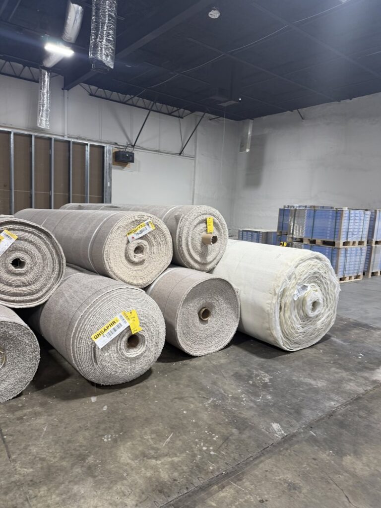 Large rolls of carpet material stored in a warehouse, ready for installation by Davis Elite Flooring in Norcross, GA.