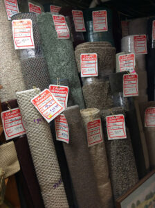 Numerous rolls of carpet remnants with price tags displayed for sale at Keystone Floor Works in Philadelphia, PA