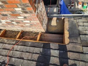 An open roof section next to a brick chimney, showing ongoing repair or installation work by The Chimney Doctor in Louisville, KY.