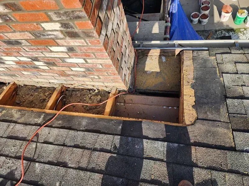 An open roof section next to a brick chimney, showing ongoing repair or installation work by The Chimney Doctor in Louisville, KY.