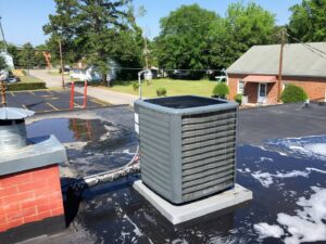 An outdoor AC unit on a commercial rooftop undergoing maintenance or cleaning by Deon Arnold Heating & Air Conditioning in Fayetteville, NC