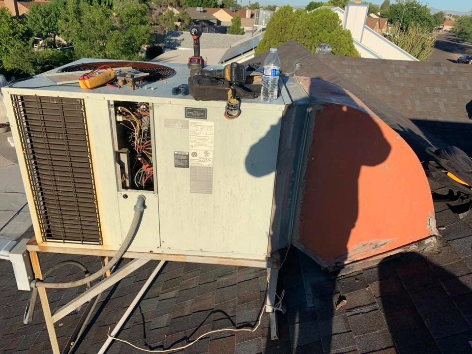A rooftop AC unit with its panel open, showing internal components during a repair or maintenance service by Arizaz Heating & Cooling in Chandler, AZ.