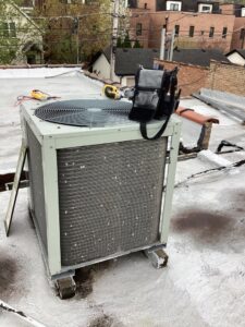 A rooftop air conditioning unit with tools on top, indicating ongoing service by Service Champions Heating & Cooling in Aurora, IL.