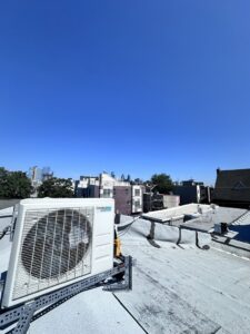 A ComfortStar mini-split unit installed on a rooftop with the Philadelphia skyline in the background by Mueller Mechanical HVAC.