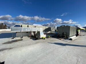Workers installing large commercial HVAC units and ductwork on a rooftop, performed by ACI Northwest Heating, Cooling & Electrical in Dalton Gardens, ID.