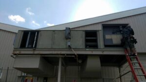 A technician servicing a large commercial HVAC unit on a rooftop for Any Climate Mechanical HVAC in Sandy, UT.