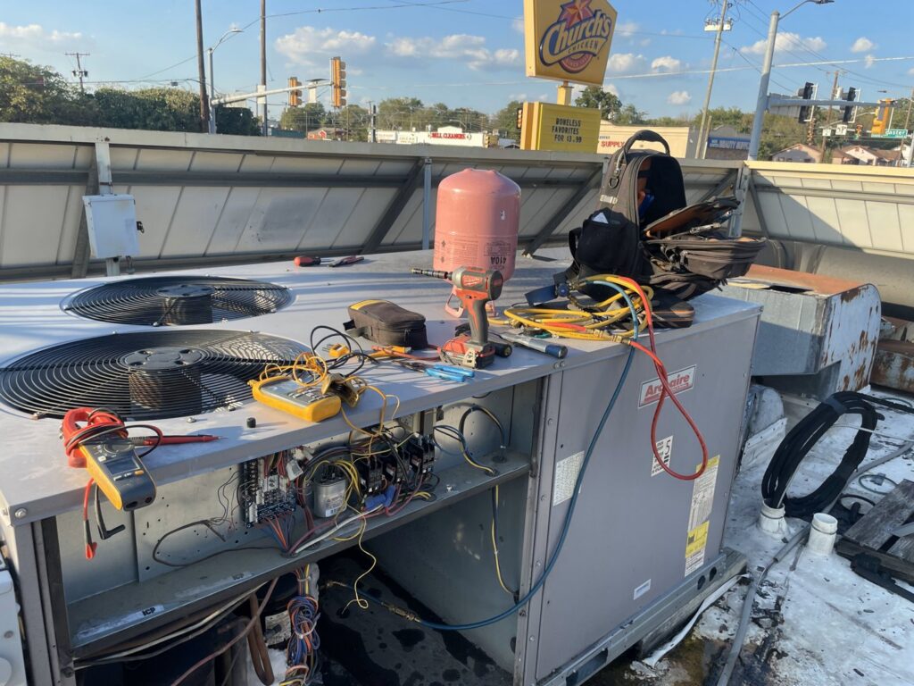 Rooftop commercial HVAC unit with tools and diagnostic equipment during service by Benavidez Heating & Air Conditioning In, Arlington, TX.