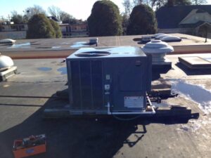 A commercial HVAC unit on a rooftop with tools nearby, indicating service by Deon Arnold Heating & Air Conditioning in Fayetteville, NC