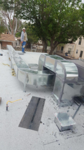 A worker installing new rooftop HVAC ductwork for Avallone Mechanical Company in Las Cruces, NM.