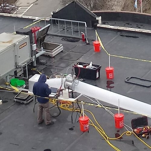 A technician performing rooftop HVAC duct sealing and testing for Aspen Air Duct Cleaning in Methuen, MA.