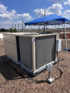 A rooftop HVAC unit being serviced under a blue canopy by Jupitair in Frisco, TX, on a sunny day.