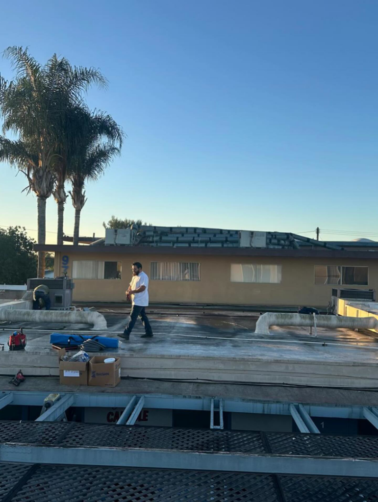 An HVAC technician performing service on a commercial rooftop unit for Rosales Aire Inc. in Anaheim, CA.