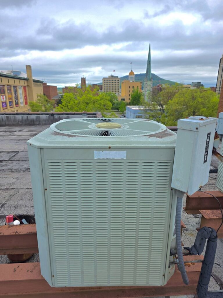 A rooftop HVAC unit with a city skyline in the background, installed by Bruce Heating & Air in Kennewick, WA.