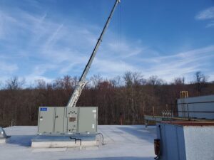 A rooftop HVAC unit being installed or replaced with a crane by Capitol Heating and Air in Morgantown, PA.
