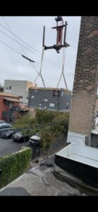 A large rooftop HVAC unit being lifted by a crane for installation by JL Heating & AC LLC in Chicago, IL