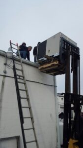 Workers installing a new rooftop HVAC unit with a forklift for Allwaysthere Heating and Cooling in Frederick, MD