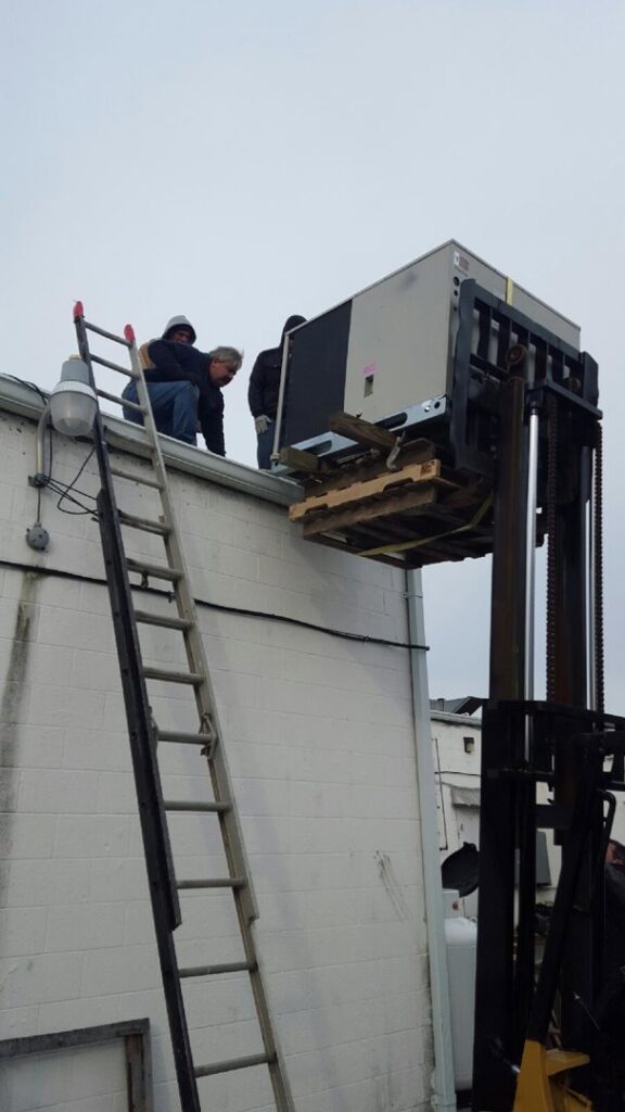 Workers installing a new rooftop HVAC unit with a forklift for Allwaysthere Heating and Cooling in Frederick, MD