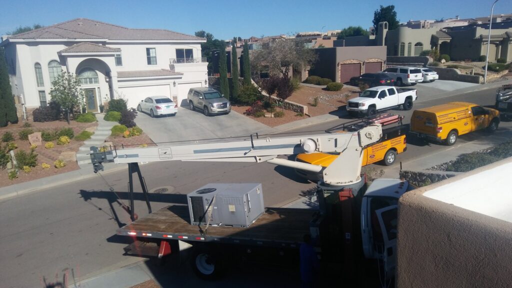 A crane truck lifting a new rooftop HVAC unit for installation by Aircon Heating and Cooling Inc in Las Cruces, NM