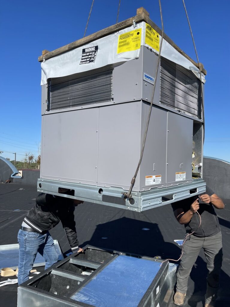 A large rooftop HVAC unit being installed by crane with technicians from KMC Heating and Cooling LLC in Clarksville, TN.