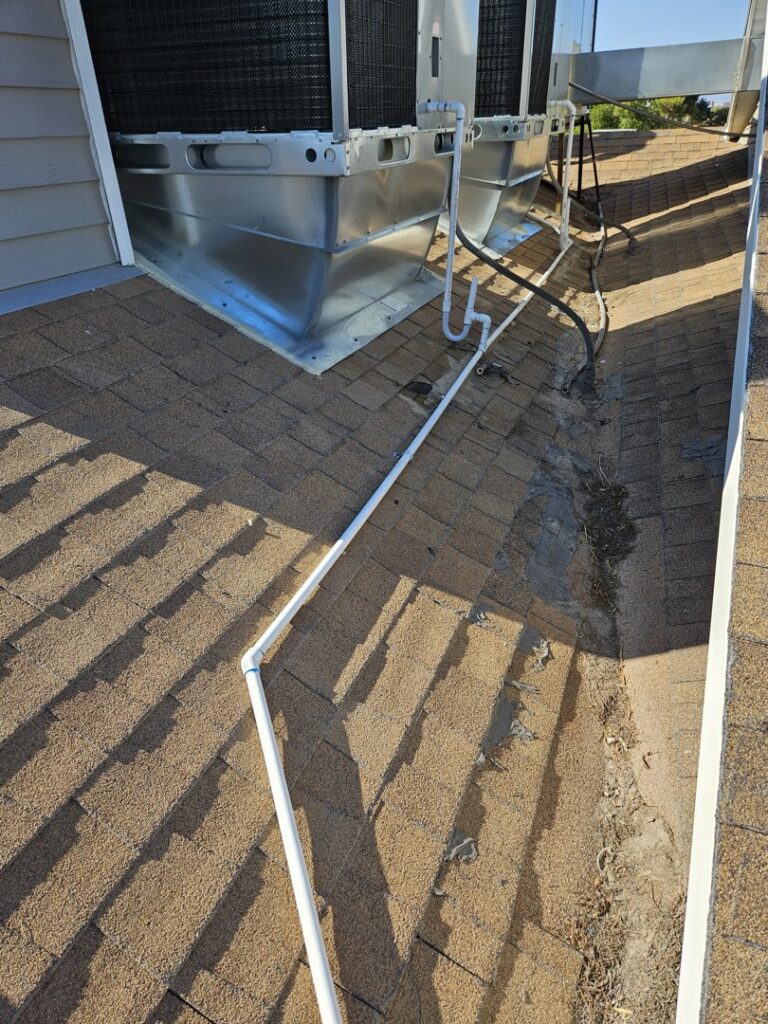 Detailed view of a rooftop HVAC unit installation with piping on a shingle roof by Colton Air Conditioning - Las Vegas in Las Vegas, NV.