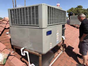 A technician installing a new rooftop HVAC unit on a tiled roof for Hellerud Air in Peoria, AZ.