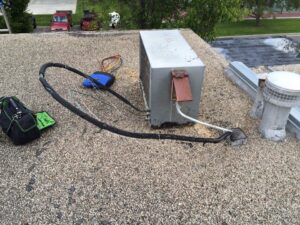 A rooftop HVAC condenser unit undergoing maintenance or repair by Bergmann Heating & Air Conditioning, LLC in Orem, UT