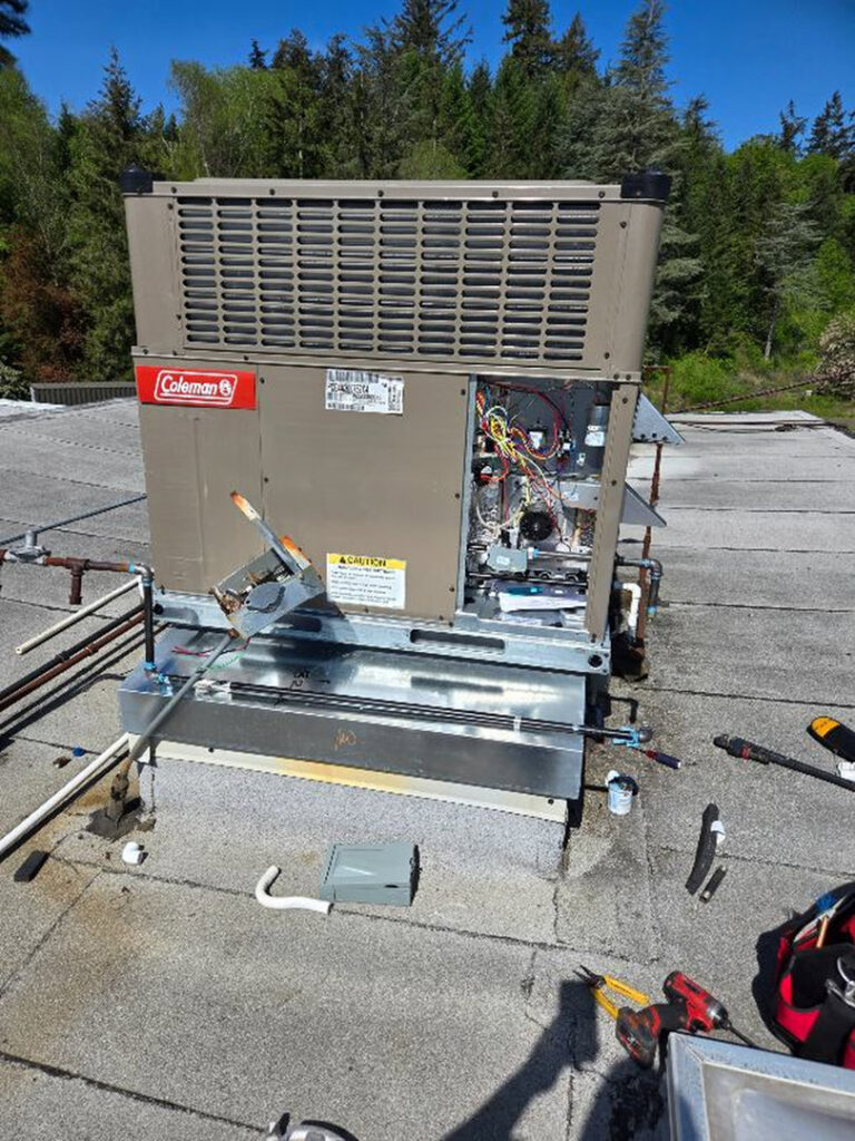 Technician performing maintenance on a Coleman rooftop HVAC unit for HVAC Ministries LLC in Salem, OR