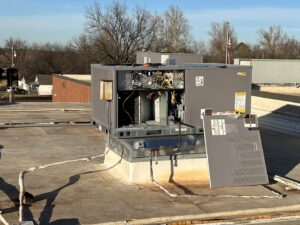 A commercial rooftop HVAC unit with panels removed for maintenance service by Trinity Climate Control in Clayton, NC.