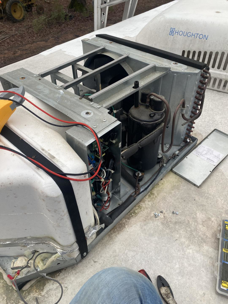 A technician repairing an open rooftop HVAC unit with exposed components for Fox Heating and Air service in Hueytown, AL.