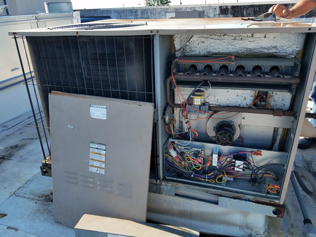 A rooftop HVAC unit with its access panel open, showing internal components during repair or maintenance by Service Pro Titans, Chicago, IL.
