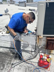 An Ultimate Air Conditioning technician performing rooftop HVAC unit repair using a torch and tools in Pearl City, HI
