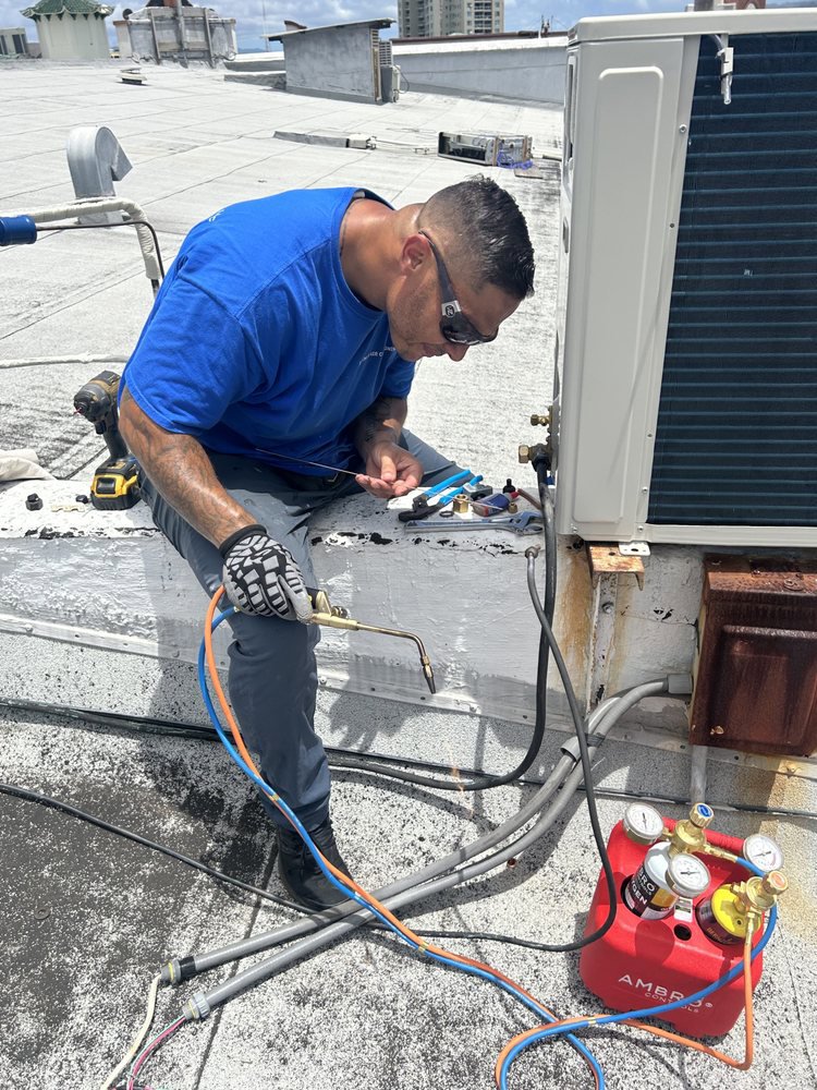 An Ultimate Air Conditioning technician performing rooftop HVAC unit repair using a torch and tools in Pearl City, HI