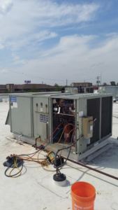 A commercial rooftop HVAC unit undergoing repair with tools and gauges by WC Heating & Cooling Corp. in West Chicago, IL.