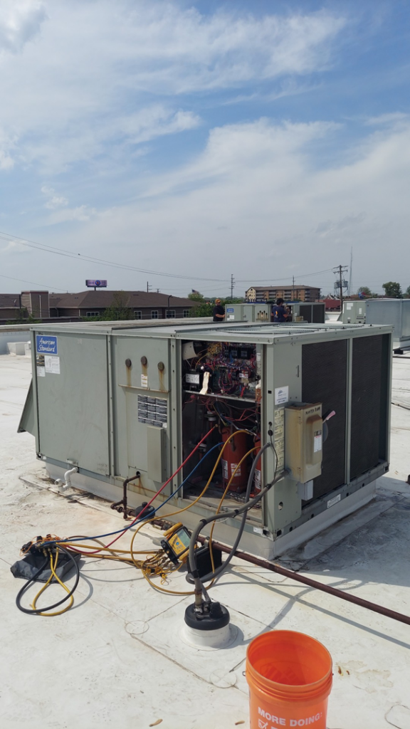 A commercial rooftop HVAC unit undergoing repair with tools and gauges by WC Heating & Cooling Corp. in West Chicago, IL.