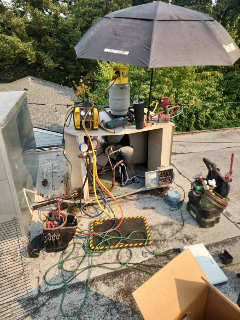 A Nelke Mechanical technician performing service and repair on a commercial rooftop HVAC unit in Keizer, OR.