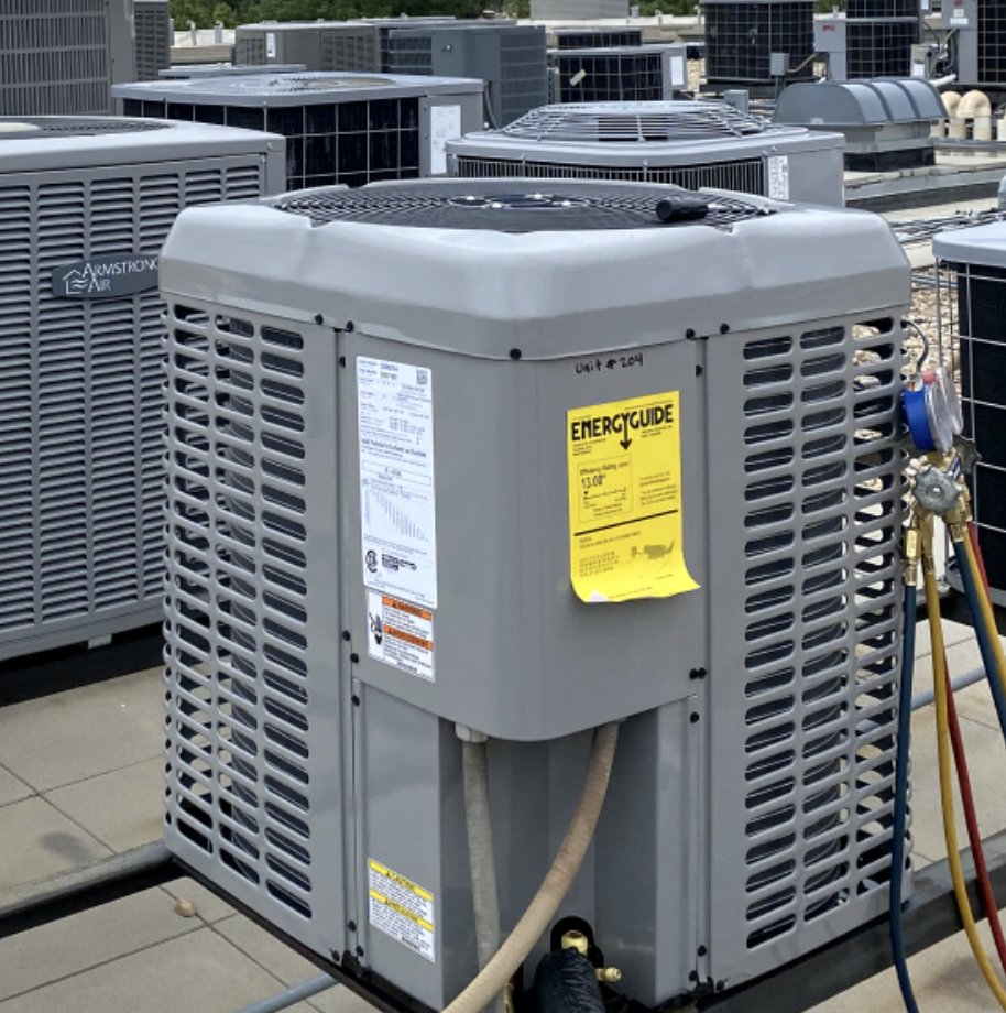 A rooftop HVAC unit being serviced with gauges attached by Husky Heating and Cooling in Westminster, CO.
