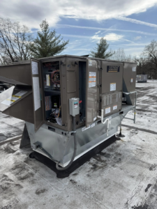 A rooftop commercial HVAC unit with open panels, showing internal components during service by Prism Heating & Air Conditioning in Toms River, NJ.
