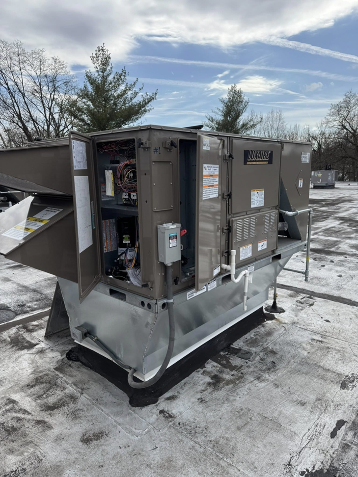 A rooftop commercial HVAC unit with open panels, showing internal components during service by Prism Heating & Air Conditioning in Toms River, NJ.