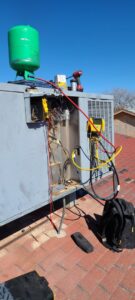 A rooftop HVAC unit undergoing service with gauges and tools by Reading Plumbing, Heating & Air Conditioning in Roswell, NM