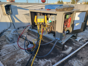 A commercial rooftop HVAC unit undergoing service with gauges connected by Santos Heating and Cooling in St Joseph, MO.
