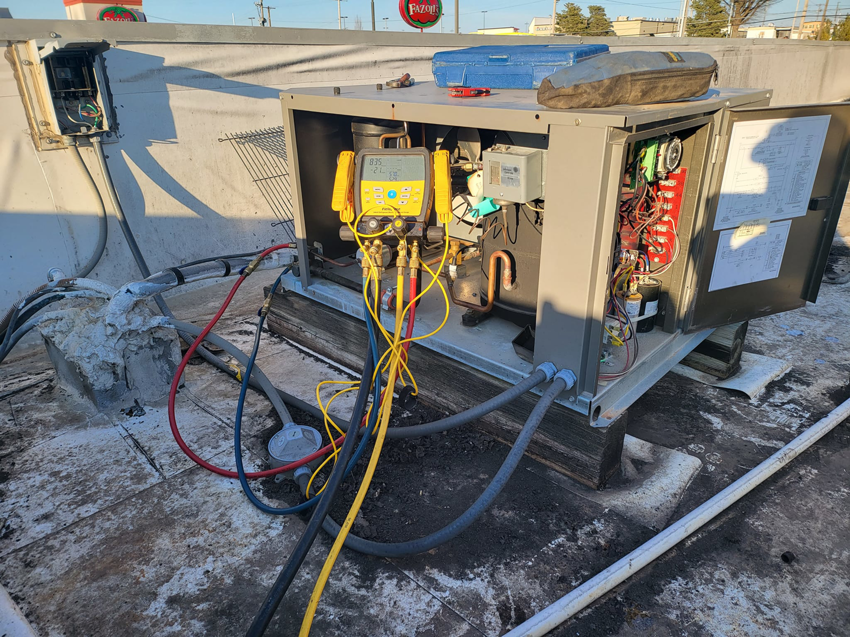 A commercial rooftop HVAC unit undergoing service with gauges connected by Santos Heating and Cooling in St Joseph, MO.